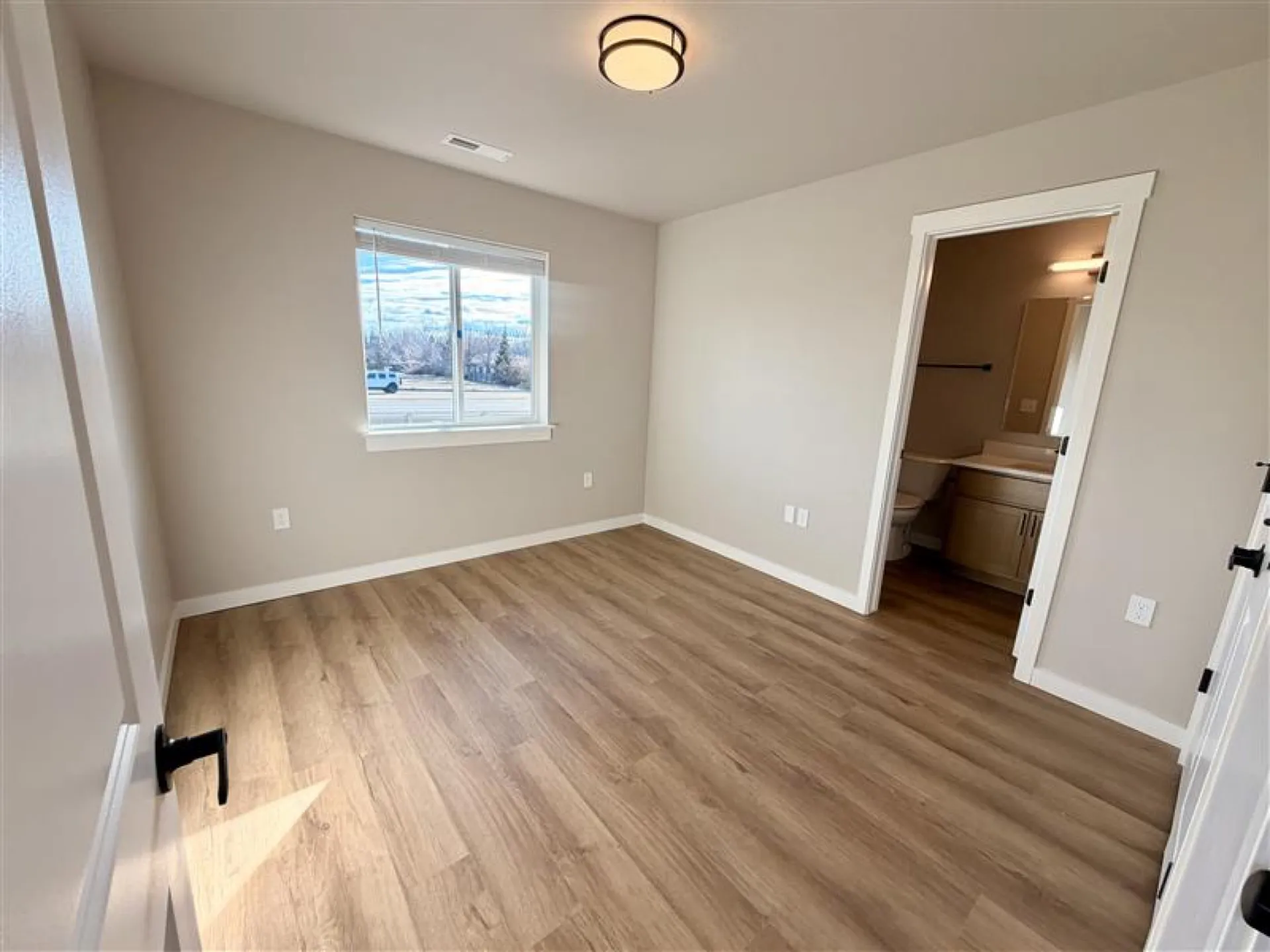 Spacious second bedroom with large egress window and luxury vinyl plank flooring in a Boise townhome